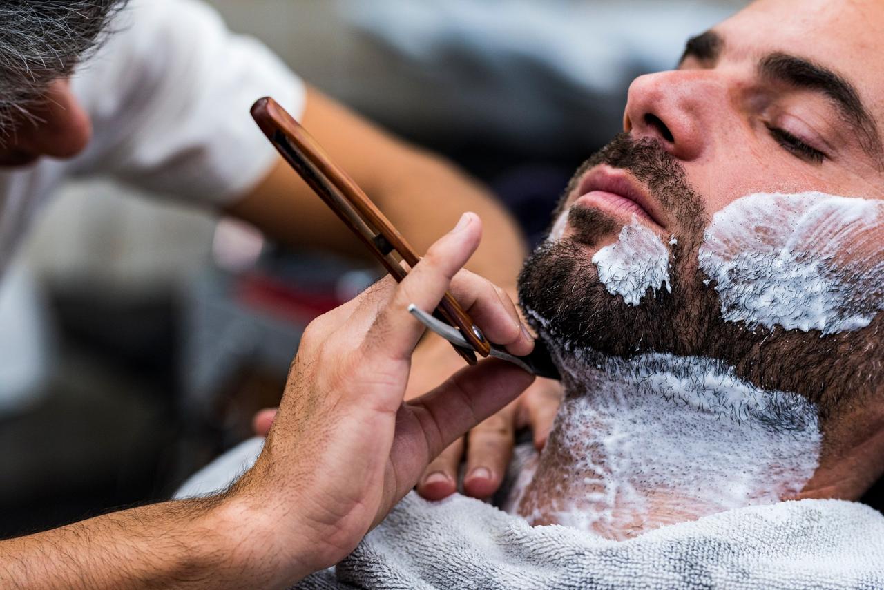 Un hombre se afeita frente a un espejo espuma de afeitar